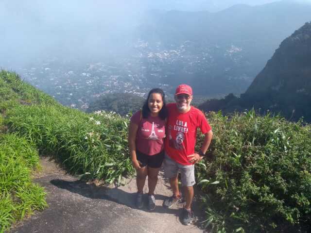 Foto na Pedra da Gávea/RJ onde eu, de camisa vermelha estou ao lado da filhota que sorri para a foto! Ao fundo,a cidade do Rio de Janeiro por trás de uma névoa. 